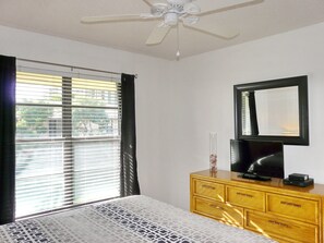 A bedroom with a bed, a dresser, a television, and a ceiling fan.