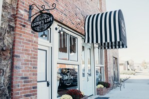 Step into Lottie's Loft, a charming storefront with a black and white striped awning and a welcoming entrance.