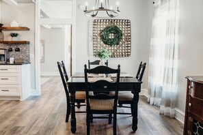 Enjoy meals in this inviting dining area with a table for four, a decorative wreath, and a chandelier.