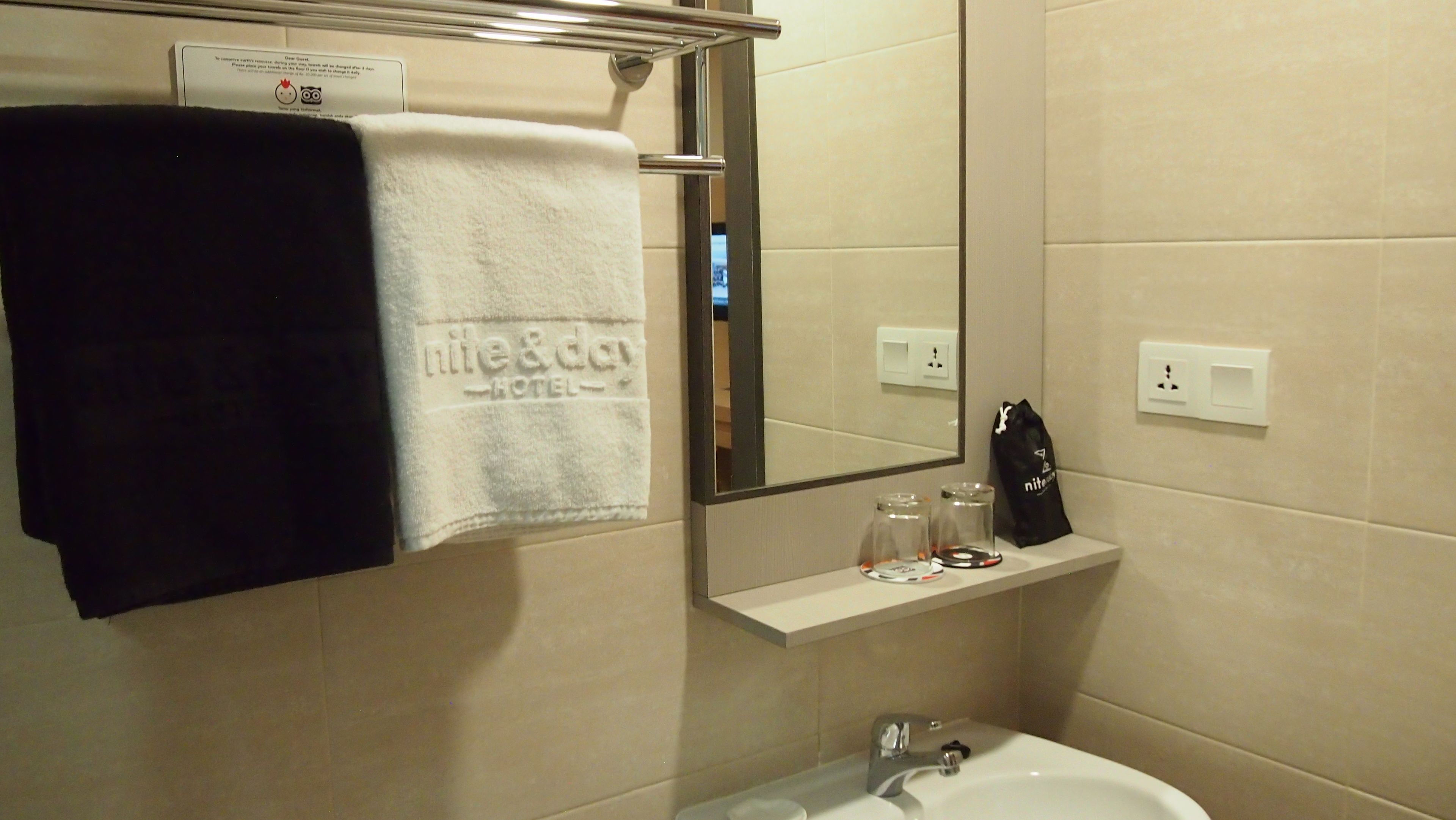 A bathroom with a sink, mirror, towel rack, and a shelf with toiletries.