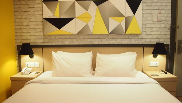 A hotel room with a bed, two bedside lamps, a phone, and a wall clock.