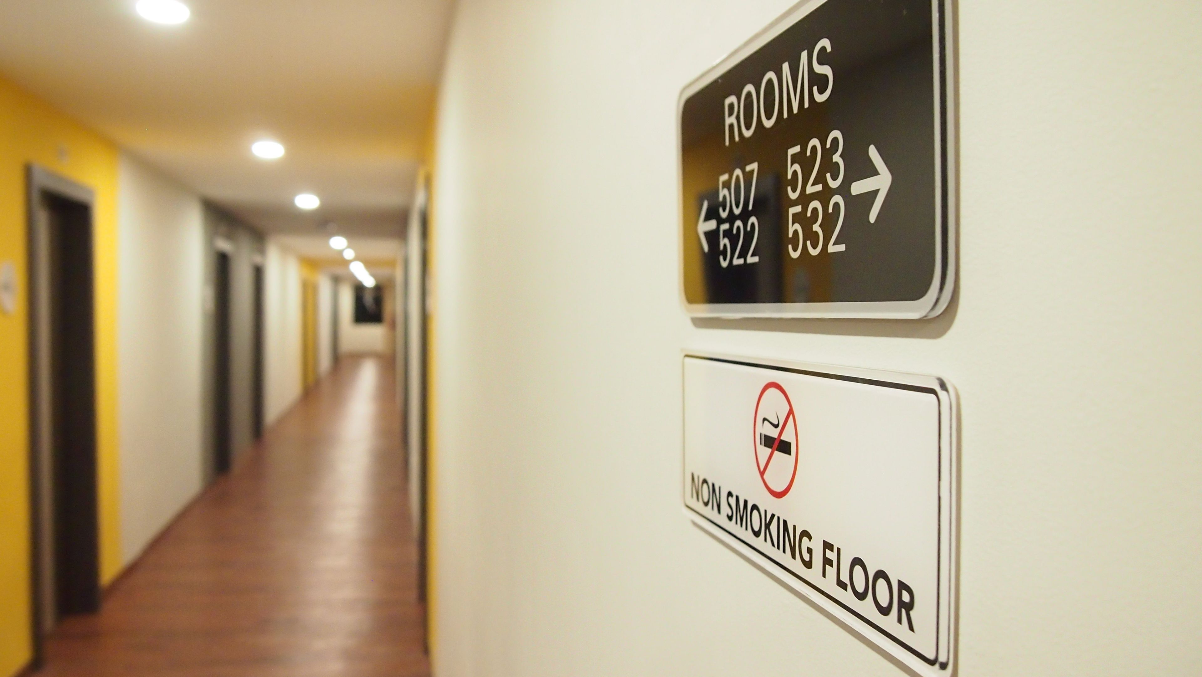 A hotel corridor with directional signs for rooms and a no-smoking floor sign.
