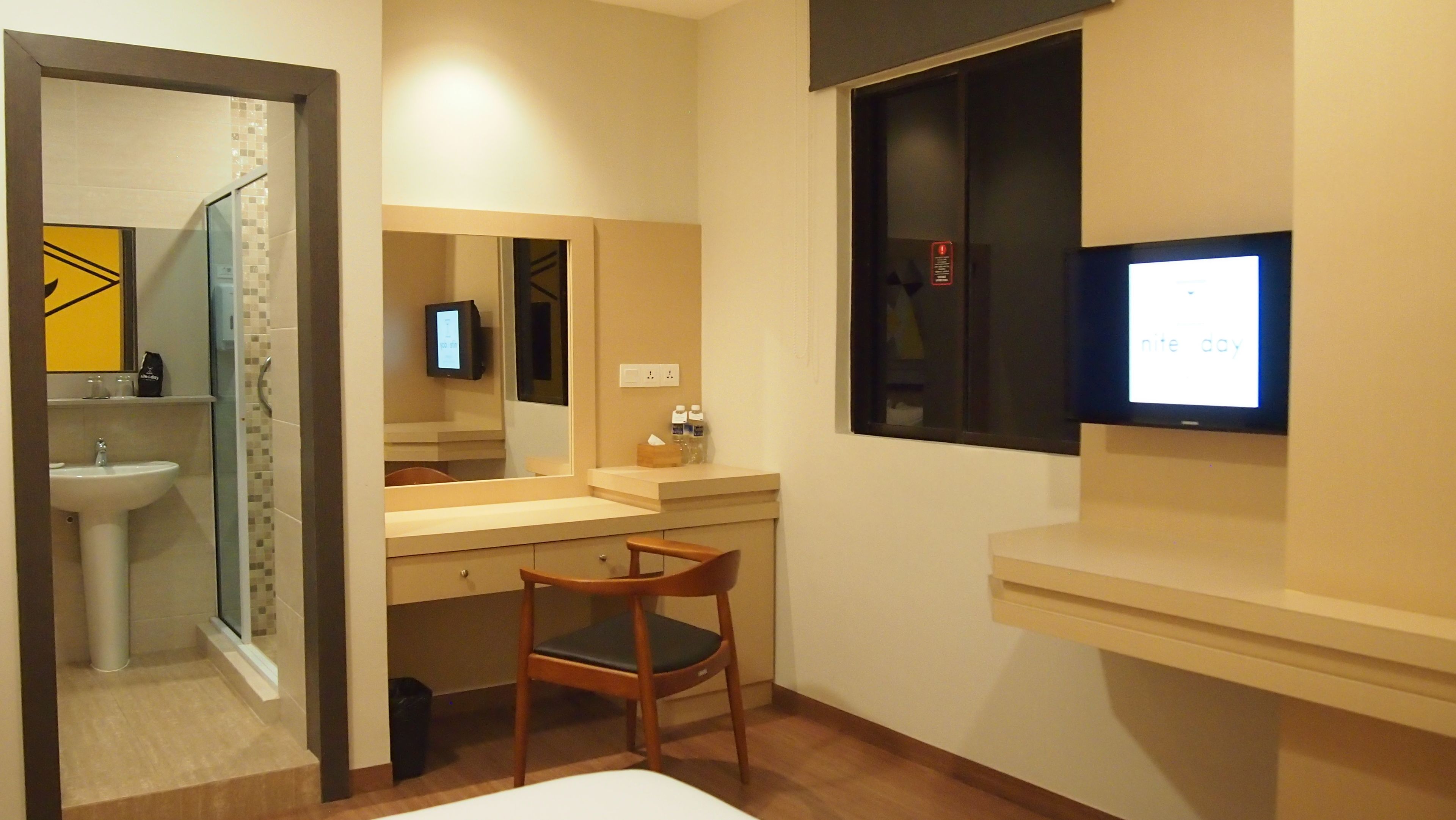 A modern bathroom with a sink, mirror, and a television mounted on the wall.
