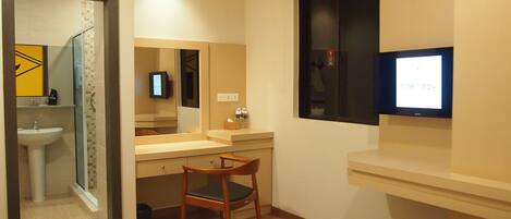 A modern bathroom with a sink, mirror, and a television mounted on the wall.