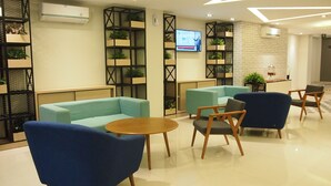 A modern lobby with seating areas, a TV screen, and decorative plants. - Nite & Day Laguna Bintan - Tanjungpinang (Tanjung Pinang)