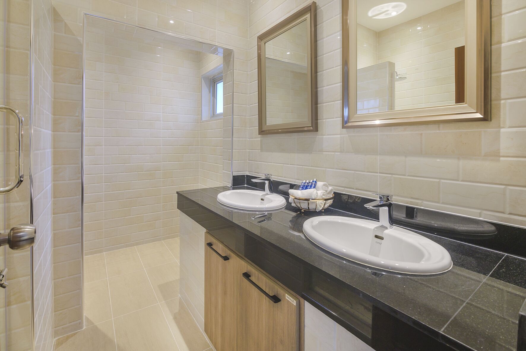 Une salle de bain moderne avec deux lavabos, une douche et un grand miroir.