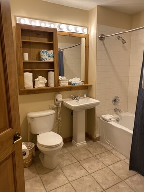 Features a vanity area with a pedestal sink and bathtub.