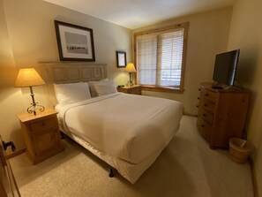 Relax in a cozy space with a large bed, two bedside tables, and a dresser with a TV.