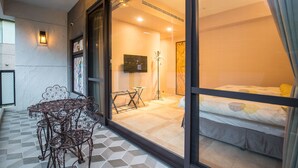 A room with a bed, a small table with chairs, and a large window with a view. - A walk in the mist (Lugu)