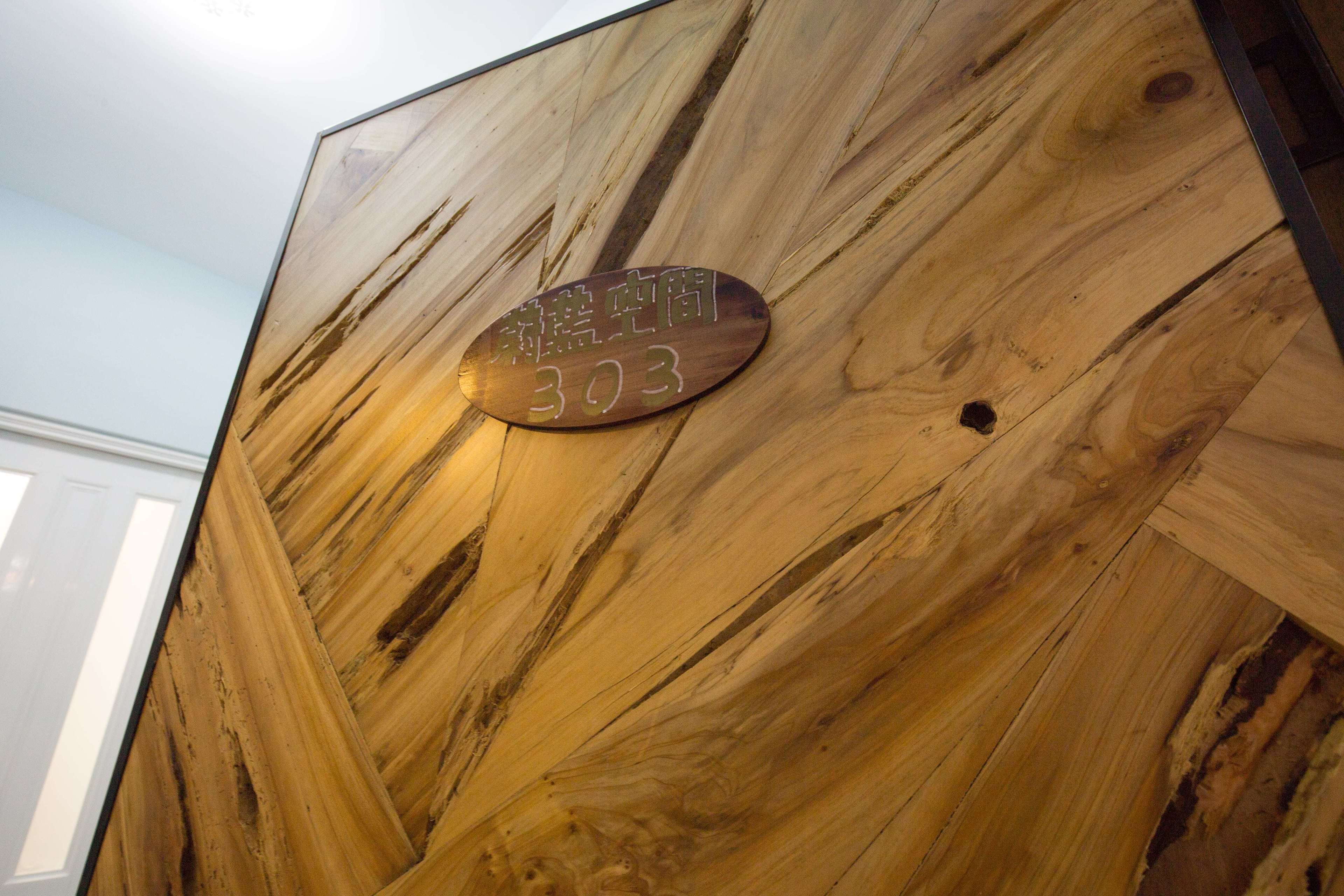 A wooden wall with a plaque displaying the number 303.