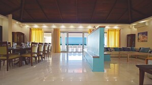 Uma sala ampla com conjunto de jantar, sofá e vista através de uma porta de vidro.