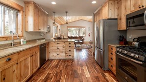 A spacious kitchen with wooden cabinets, a stainless steel refrigerator, and a large stove. - Shepherd Family Retreat- Fox | Main Home & Guest House sleeps 12 Near Yellowstone (West Yellowstone)