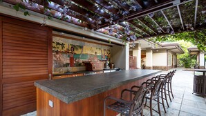 A bar area with a long counter, multiple bar stools, and a tiled floor. - HO'OLEI #24-3-BEAUTIFULLY APPOINTED VILLA-SLEEPS 10-METICULOUS CLEANING (Wailea)