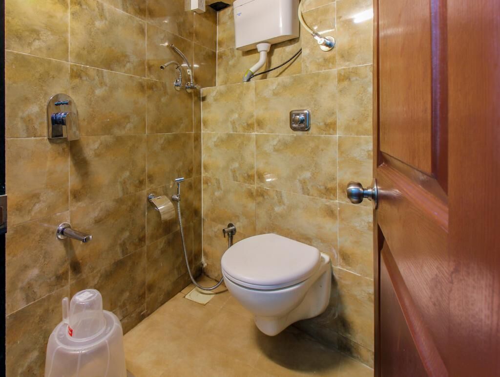 Une salle de bain équipée de toilettes, d’une douche et d’un porte-rouleau de papier toilette.