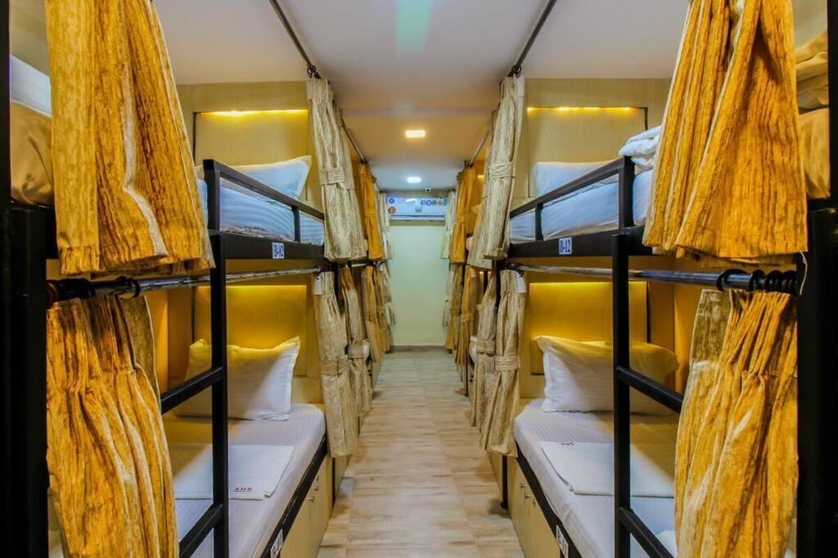 A narrow corridor with bunk beds on either side, each with a hanging towel.