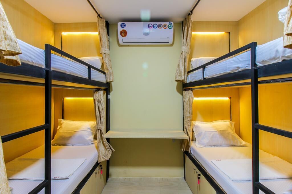 A bunk room with two beds, a small shelf, and an air conditioning unit.