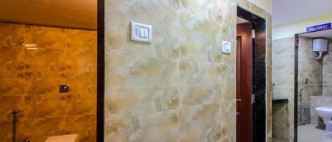 A bathroom with a toilet, shower, and a glass-enclosed sink area.
