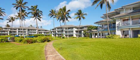 A resort with multiple-story buildings, palm trees, and a well-maintained lawn.