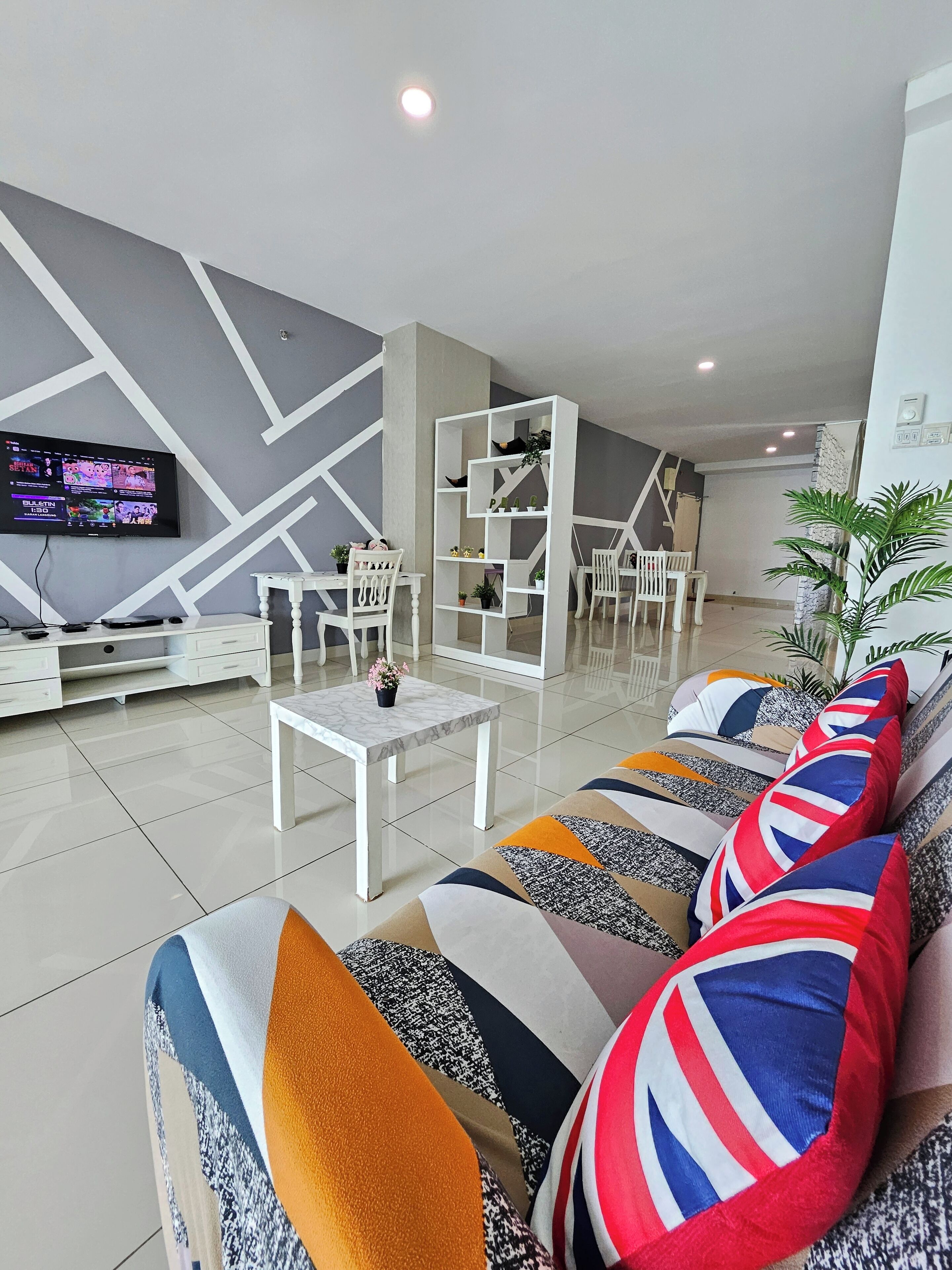 A modern living room with a sofa set, a coffee table, and a TV mounted on the wall.