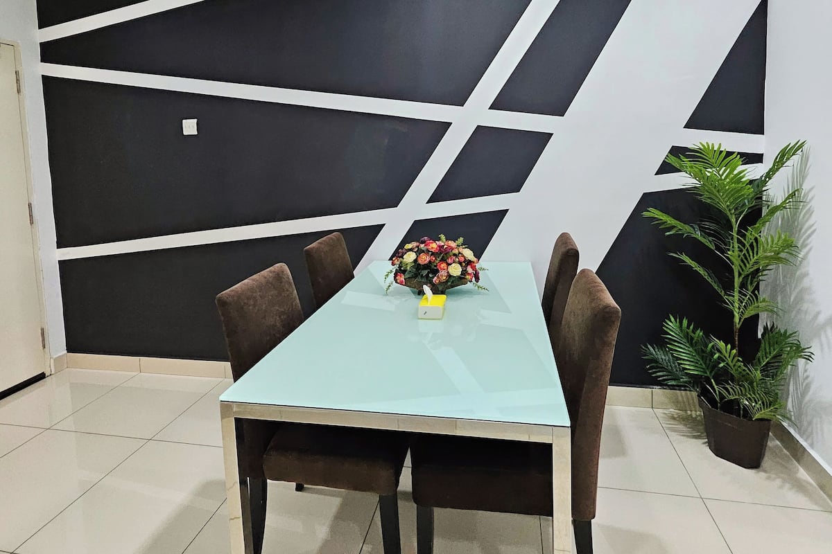 Ein Konferenzraum mit Glastisch, braunen Stühlen, einer floralen Tischdekoration und einem geometrischen Schwarz-Weiß-Wanddesign.