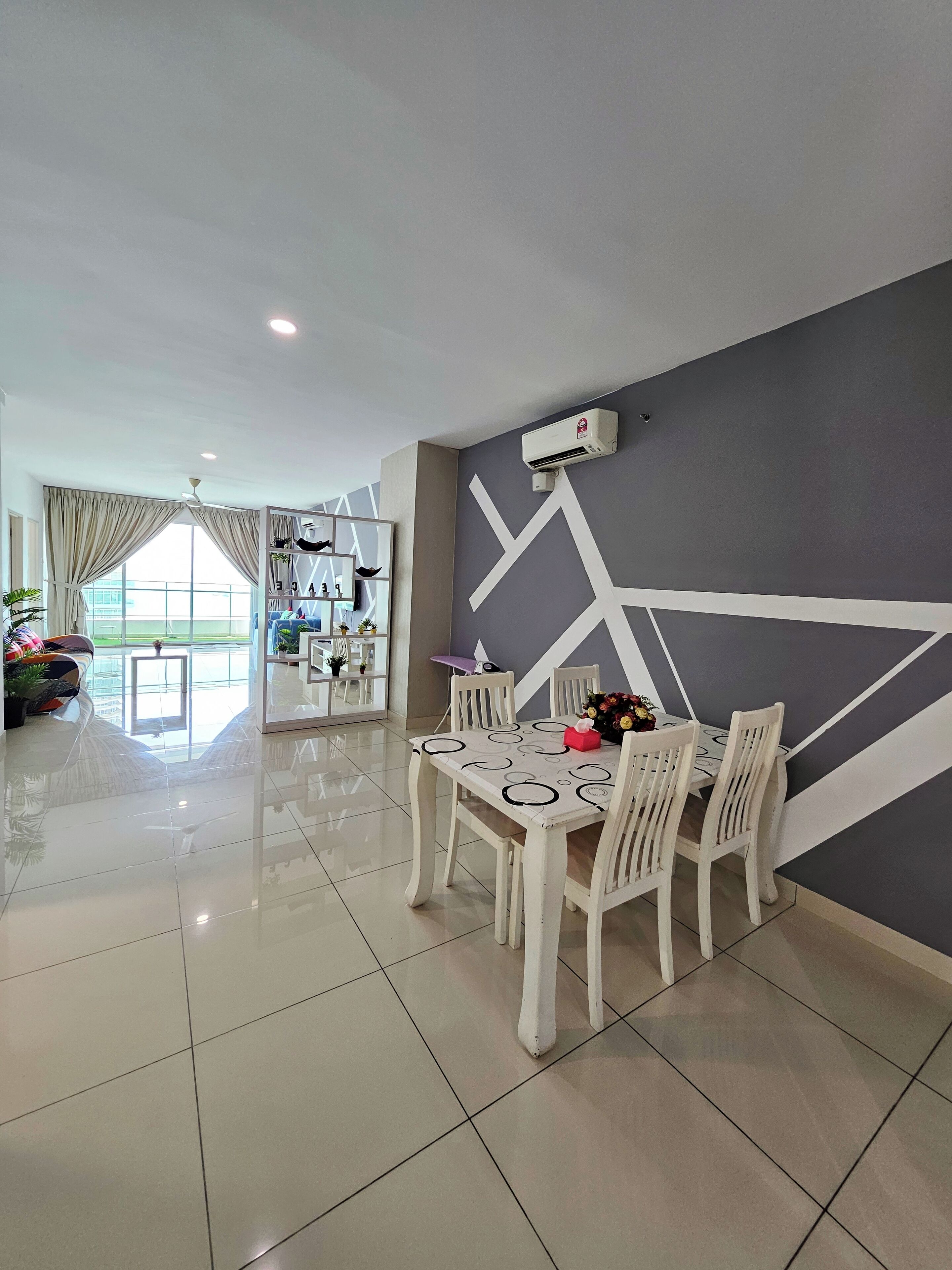 A dining area with a table set for four, a grey accent wall, and a ceiling fan.