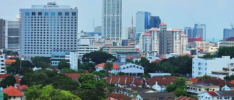 A cityscape with a prominent Hotel Royal building, surrounded by residential buildings with red-tiled roofs and a mix of modern and older architecture.