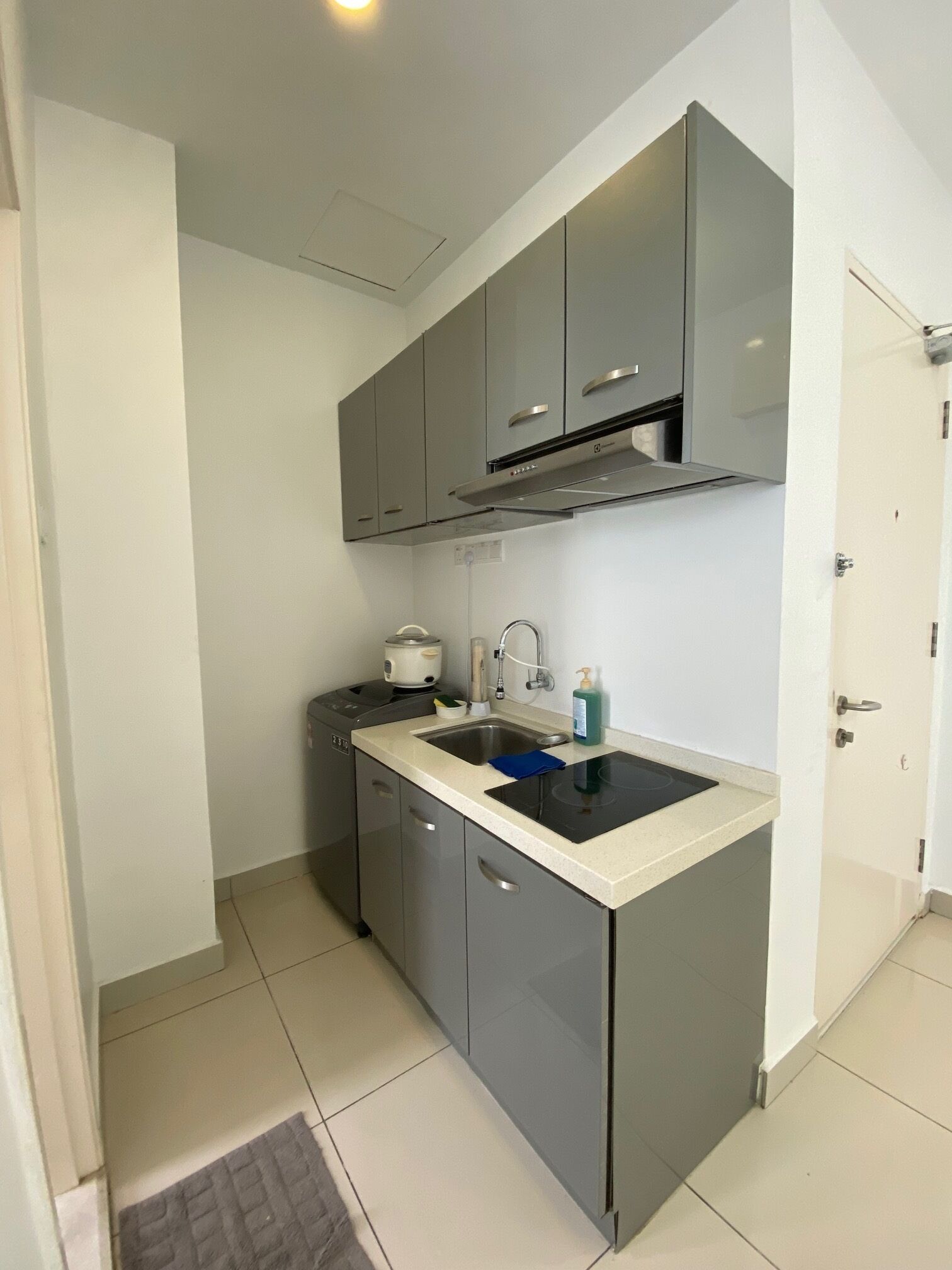A compact kitchen with grey cabinets, a black countertop, and a built-in stove.