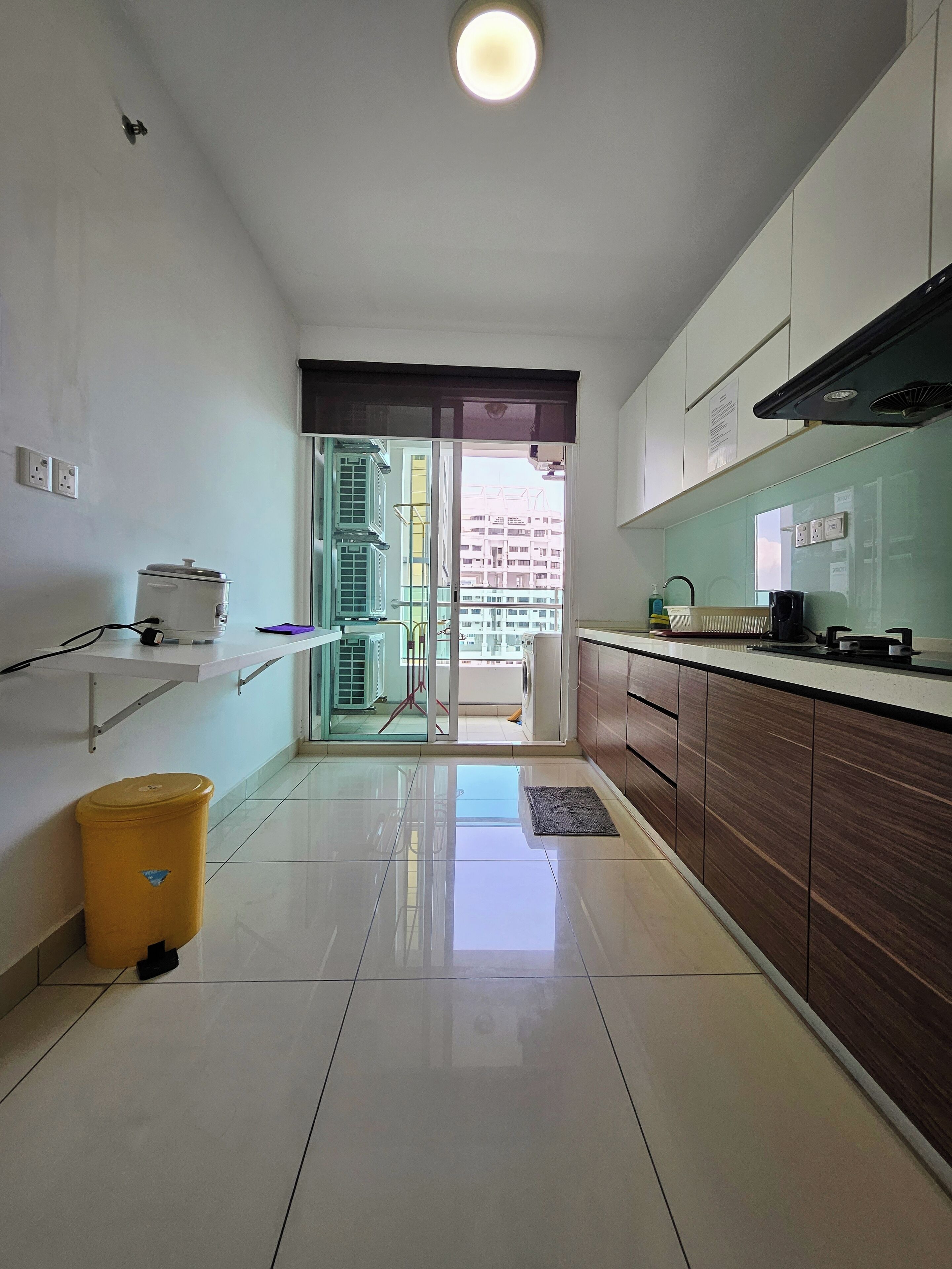 A modern kitchen with a large window, a sink, a stove, and a trash bin.
