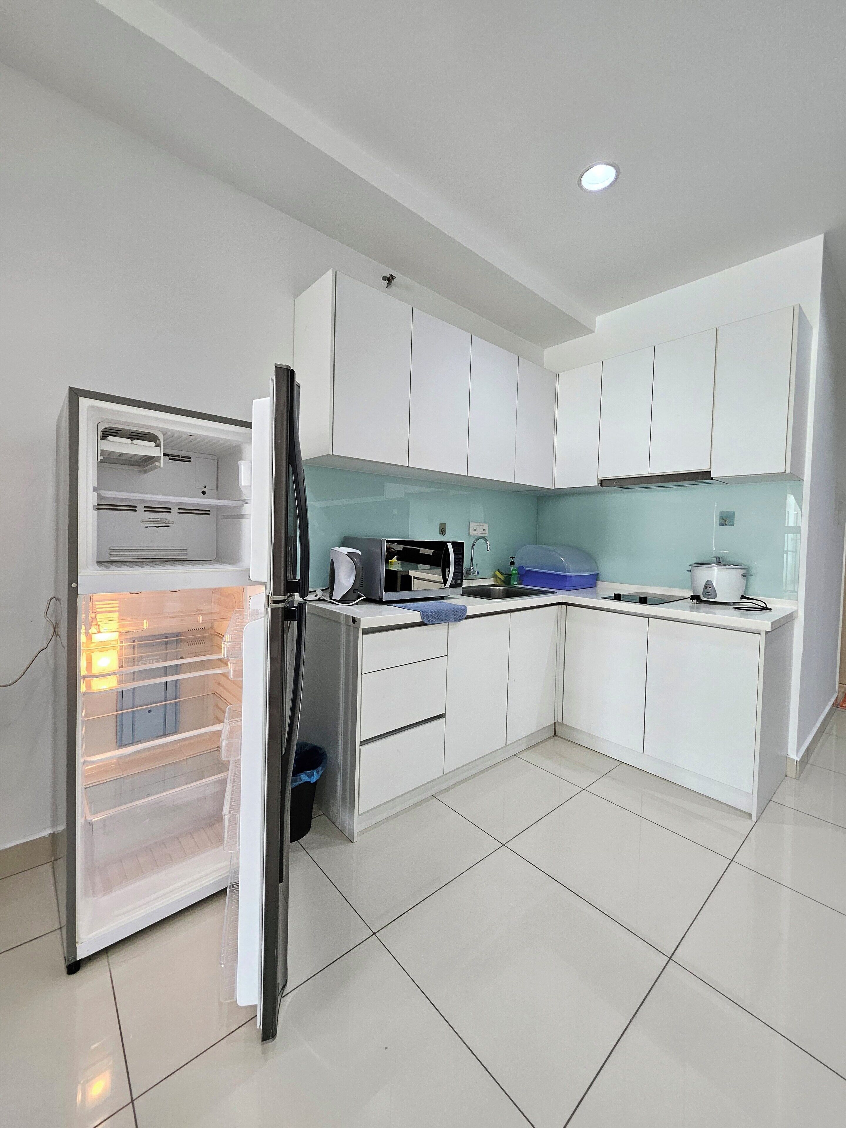 A modern kitchen with white cabinets, a built-in microwave, and a stainless steel refrigerator.