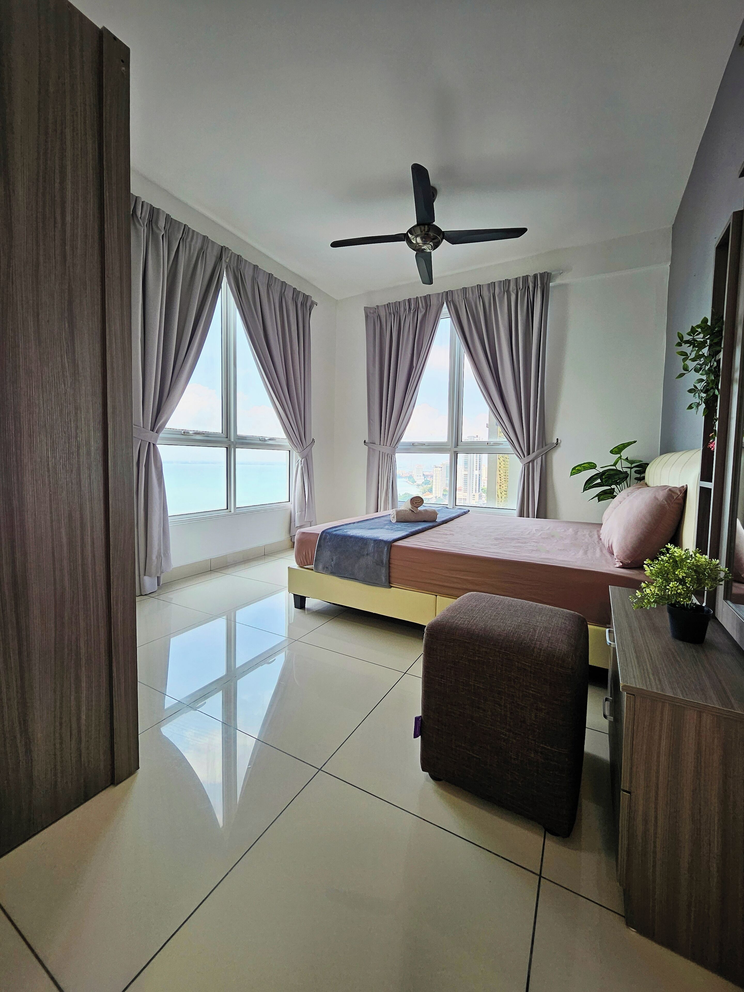 A modern hotel room with a bed, a desk, a chair, and a ceiling fan.