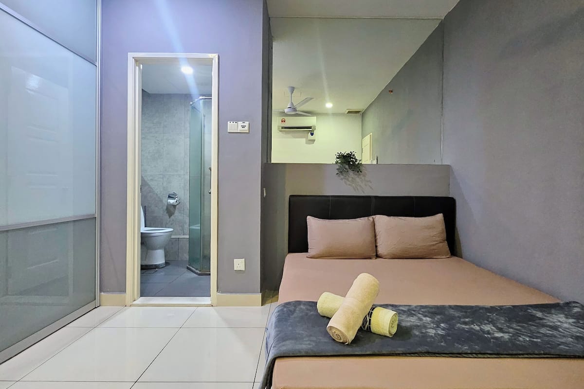 Ein modernes Schlafzimmer mit Bett, Nachttisch, Deckenventilator und einem durchgehenden Türrahmen sichtbarem Badezimmer.