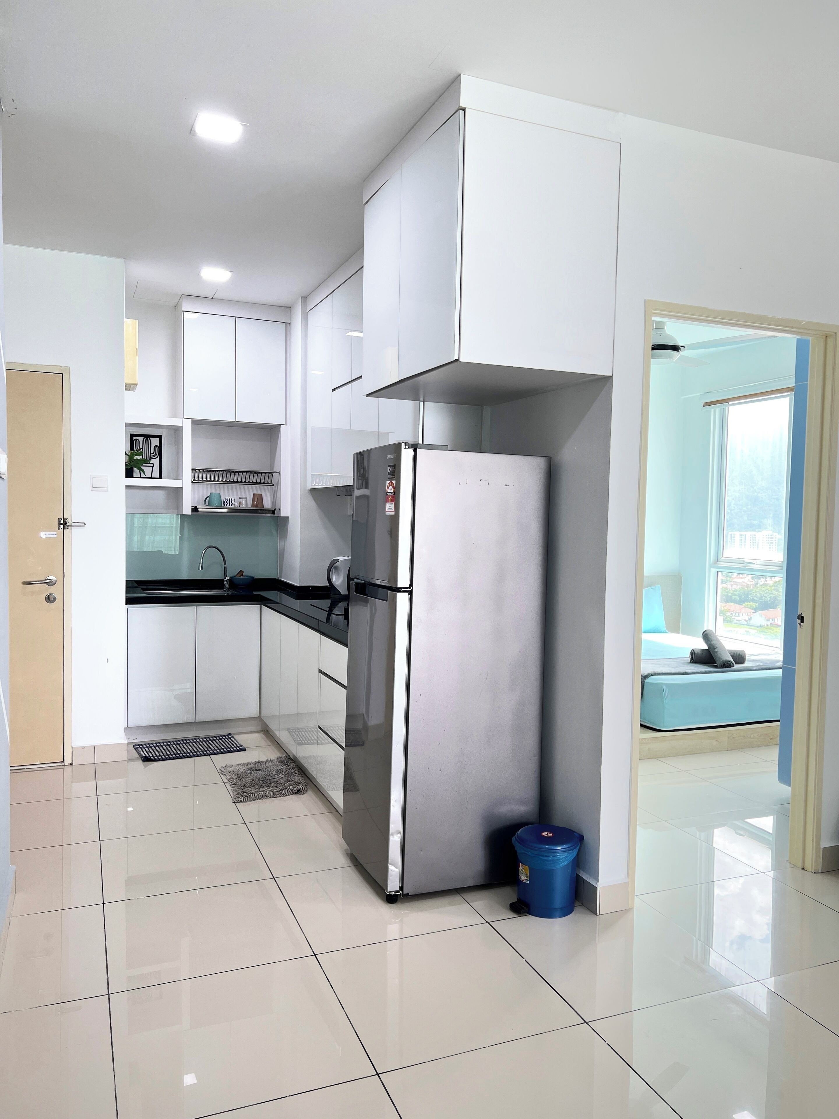 A modern kitchen with white cabinets, a stainless steel refrigerator, and a black countertop.
