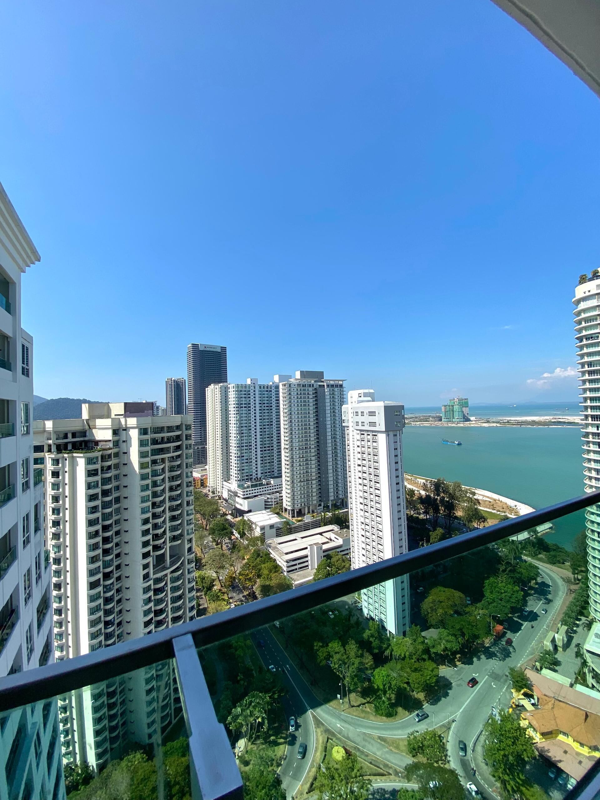 A high-rise building with multiple floors, a view of a coastal area with a body of water, and a clear blue sky.