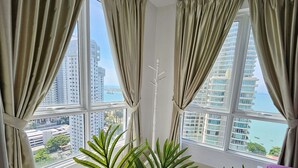 A room with large windows, a white ceiling, and a view of high-rise buildings and water. - Sky Hive Cozy Apartment Suite, Georgetown (George Town)