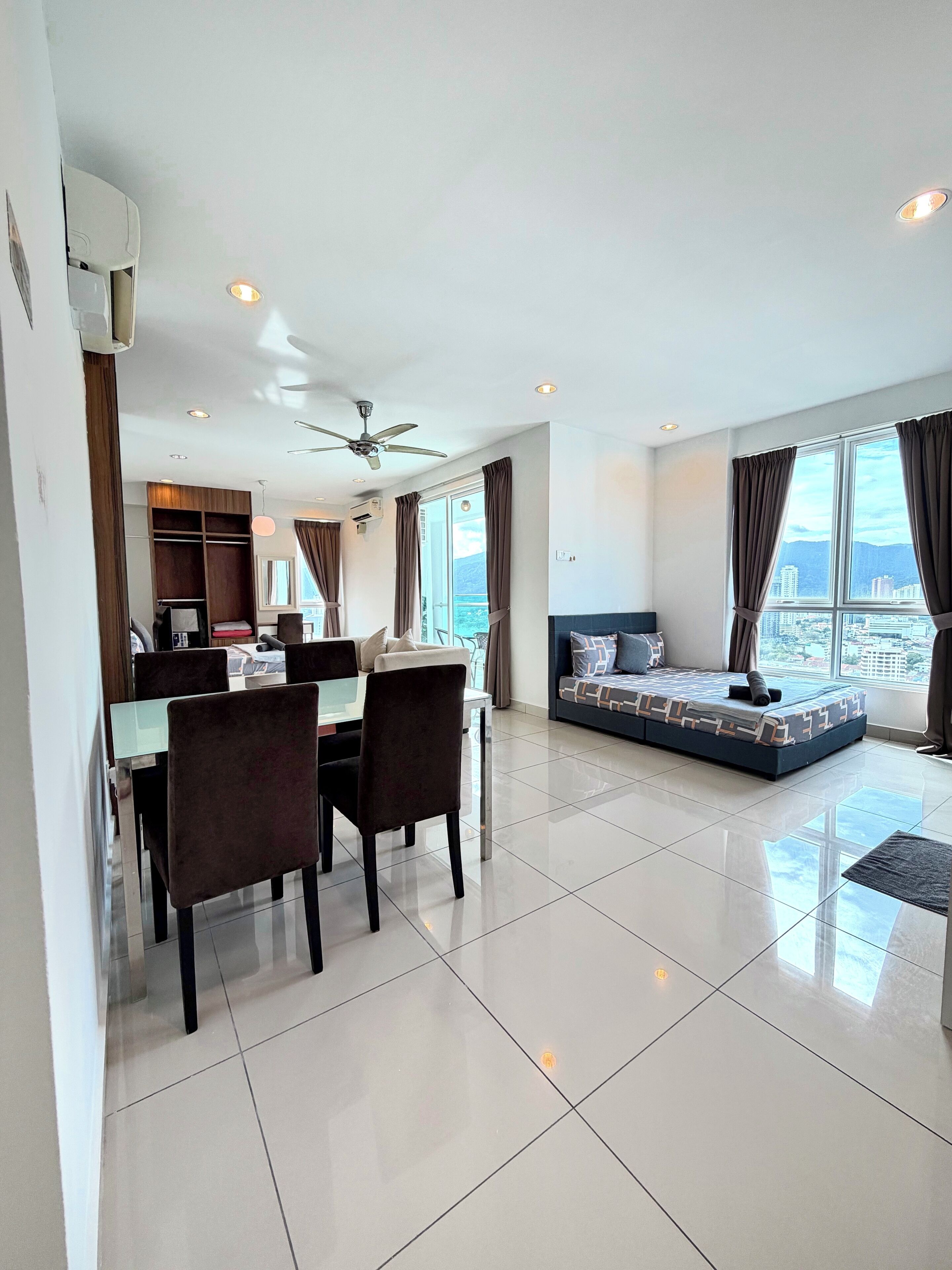 A modern living room with a dining area, a sofa bed, and a view of the city.