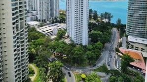 A high-rise building complex with multiple floors, surrounded by greenery and a view of the sea. - Sky Hive Cozy Apartment Suite, Georgetown (George Town)