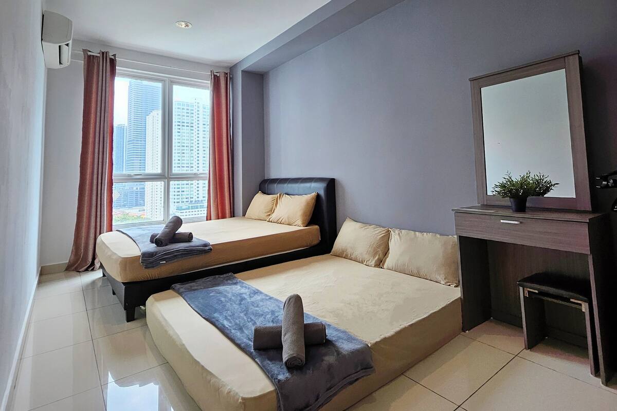 Ein modernes Hotelzimmer mit zwei Betten, einem Schreibtisch und einem großen Fenster mit Blick auf die Stadt.