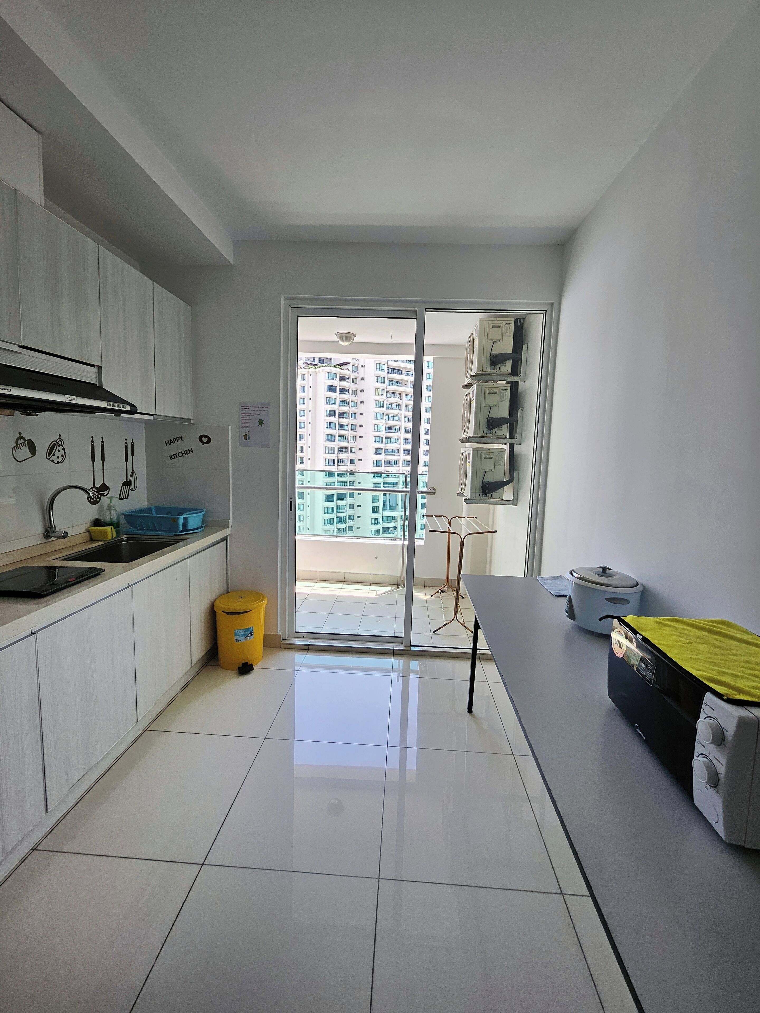Une cuisine moderne équipée d’un évier, d’une cuisinière et d’une fenêtre donnant sur un quartier résidentiel.