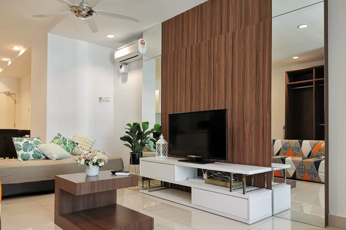 Ein modernes Wohnzimmer mit Flachbildfernseher, einer Holzwand und einer weißen Unterhaltungseinheit.