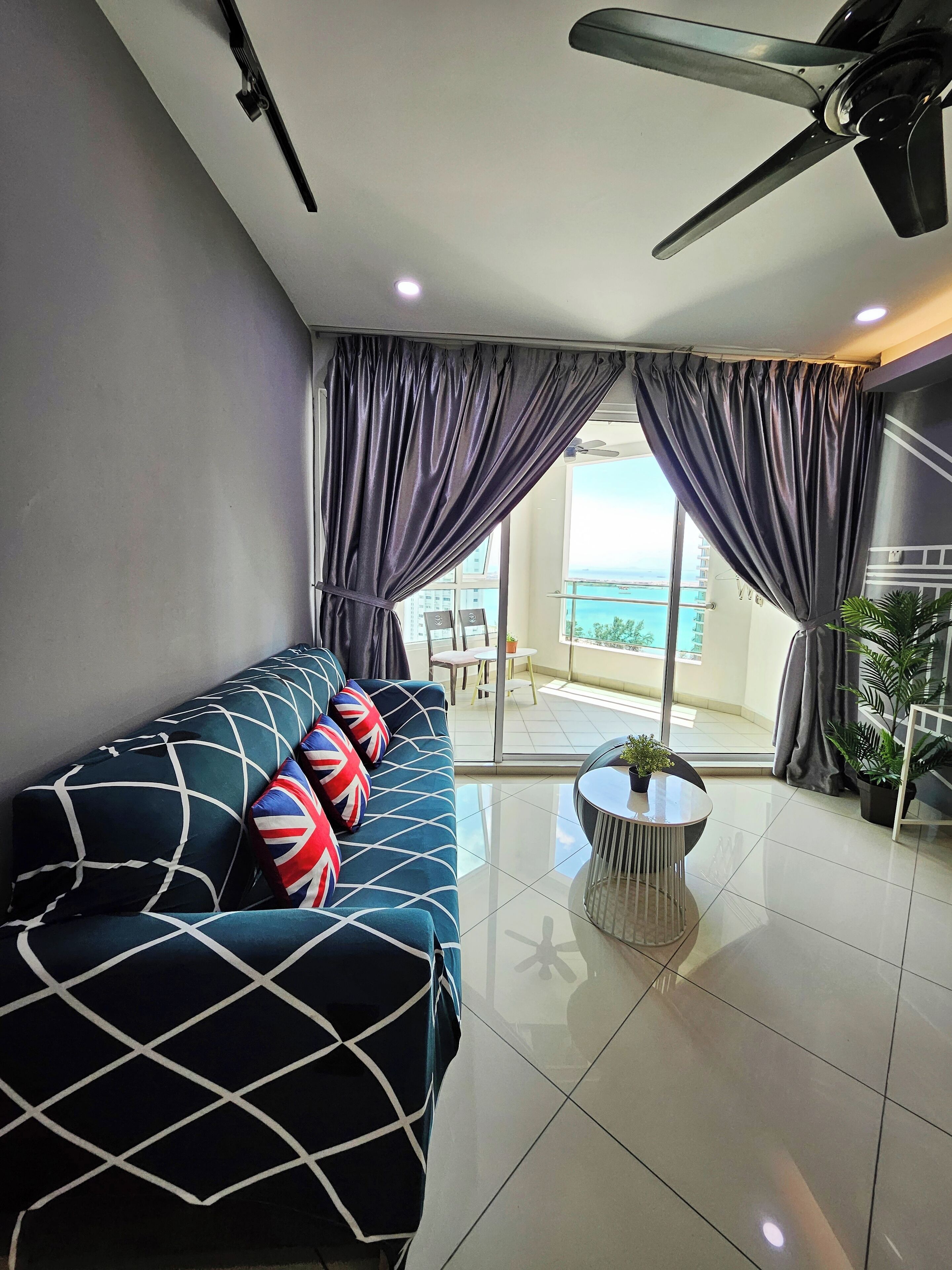 A modern living room with a sofa, a ceiling fan, and a view of the outdoors.