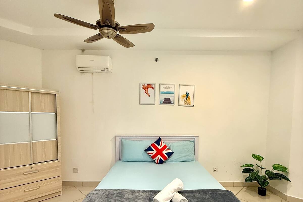 Ein Schlafzimmer mit einem Bett, einem Deckenventilator, einer Wand-Klimaanlage, einem Holzschrank und einer Topfpflanze.