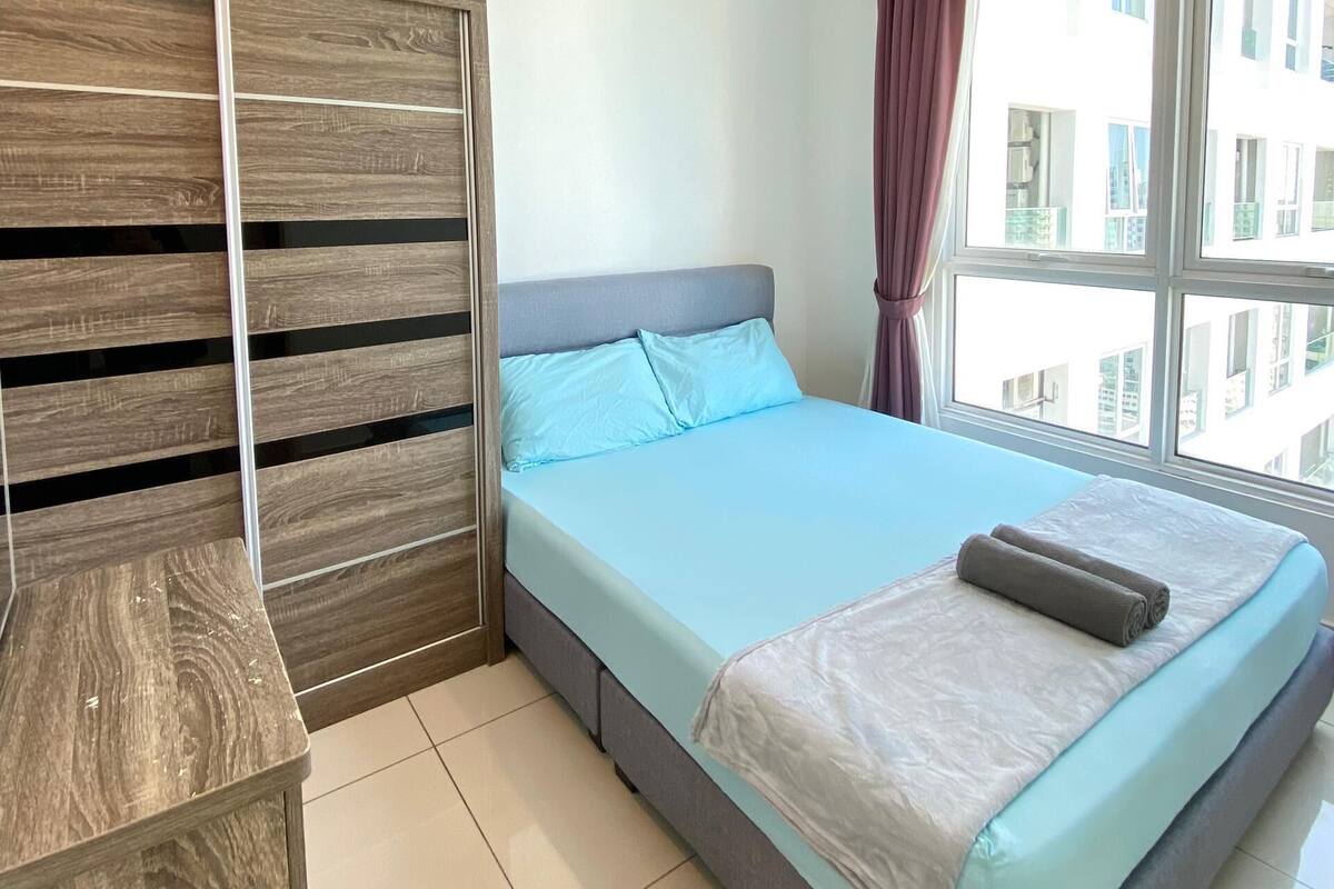 Ein Schlafzimmer mit einem Bett, einem Deckenventilator, einem Fenster mit Vorhängen und einem Holzschrank.