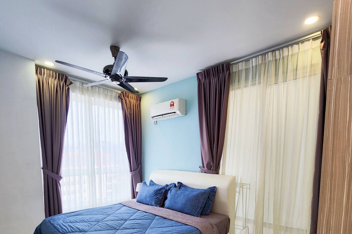 Ein modernes Schlafzimmer mit einem großen Bett, einem Deckenventilator, einer Klimaanlage und transparenten Vorhängen.