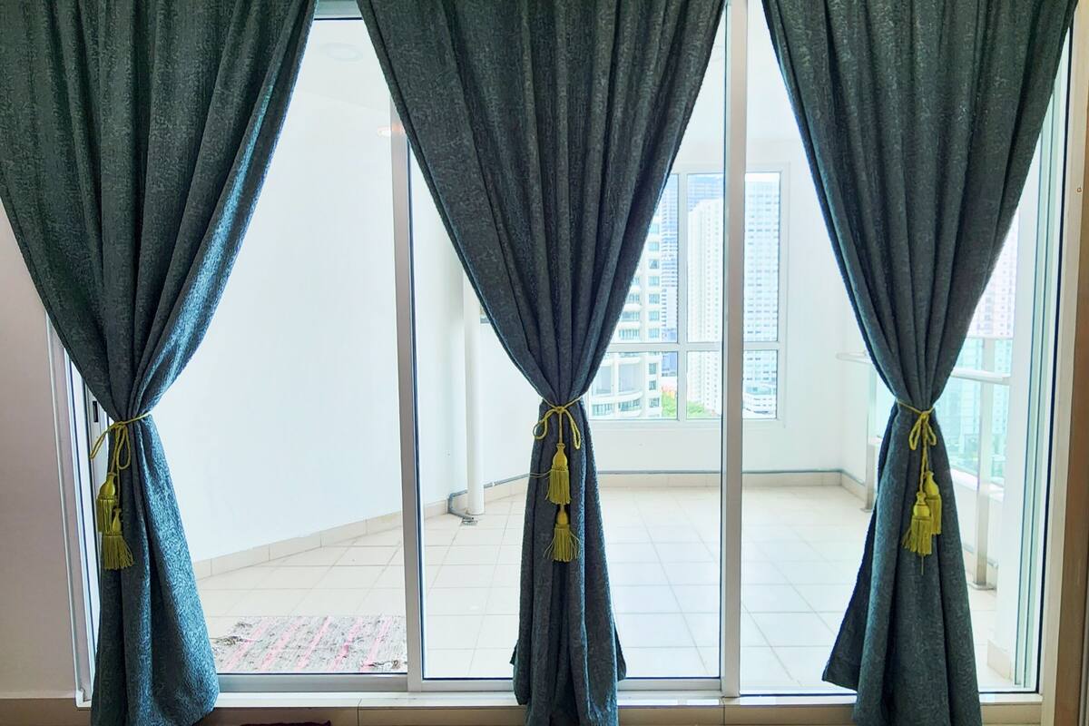 Ein Zimmer mit großen Fenstern, einem violetten Teppich und einem Deckenventilator.