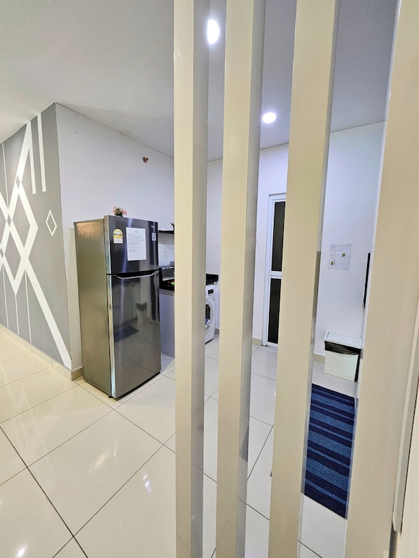 A modern kitchen with a stainless steel refrigerator, a washing machine, and a microwave. - Sky Hive Cozy Apartment Suite, Georgetown (George Town)