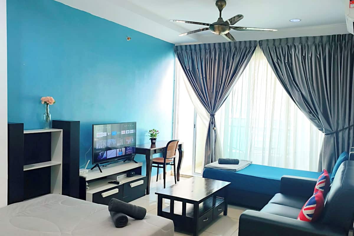 Ein modernes Wohnzimmer mit Bett, Sofa, Fernseher und Deckenventilator.