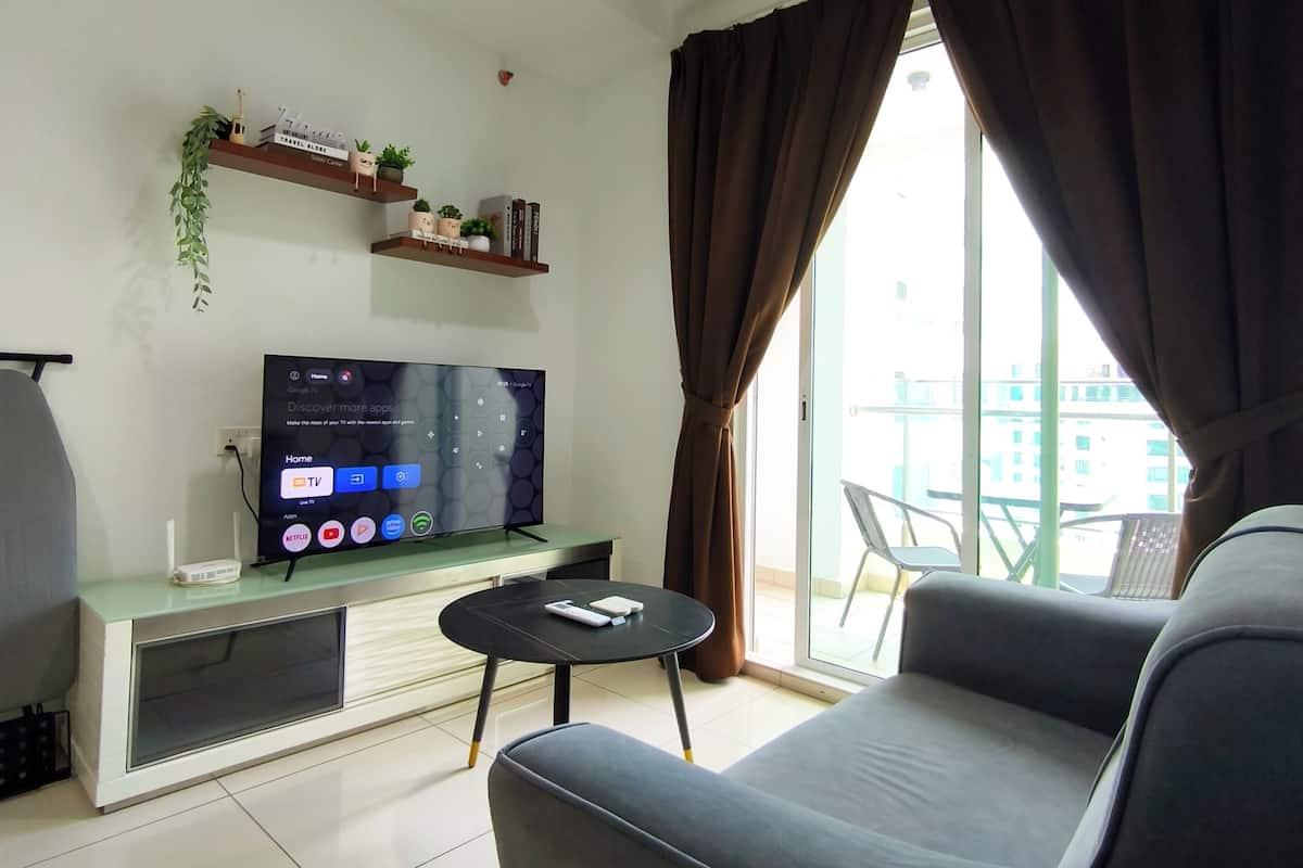 Ein Wohnzimmer mit Flachbildfernseher, Deckenventilator, Sofa, kleinem Tisch und Balkon mit Blick.