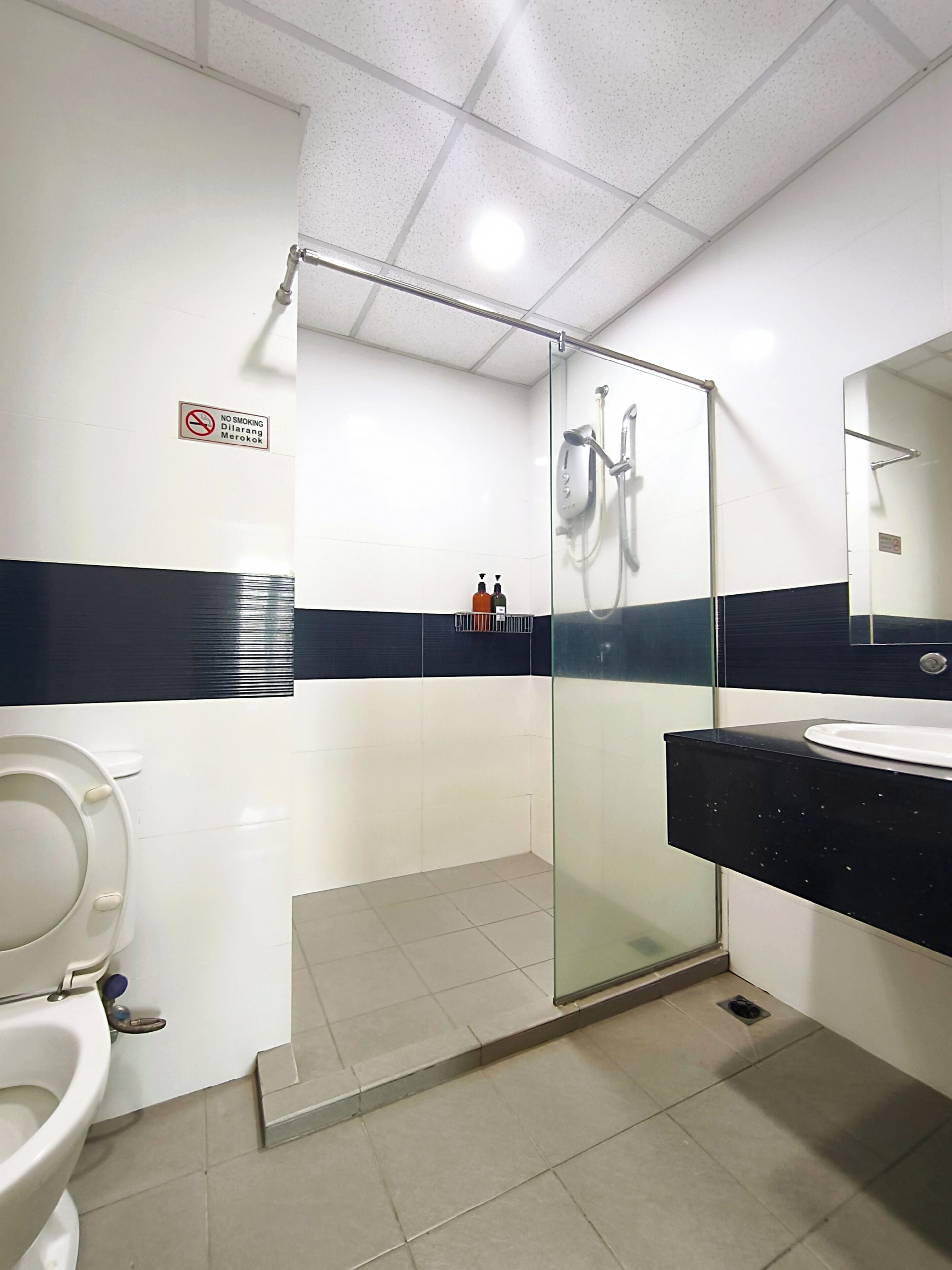 A modern bathroom with a glass-enclosed shower, a white toilet, and a black countertop with a sink.
