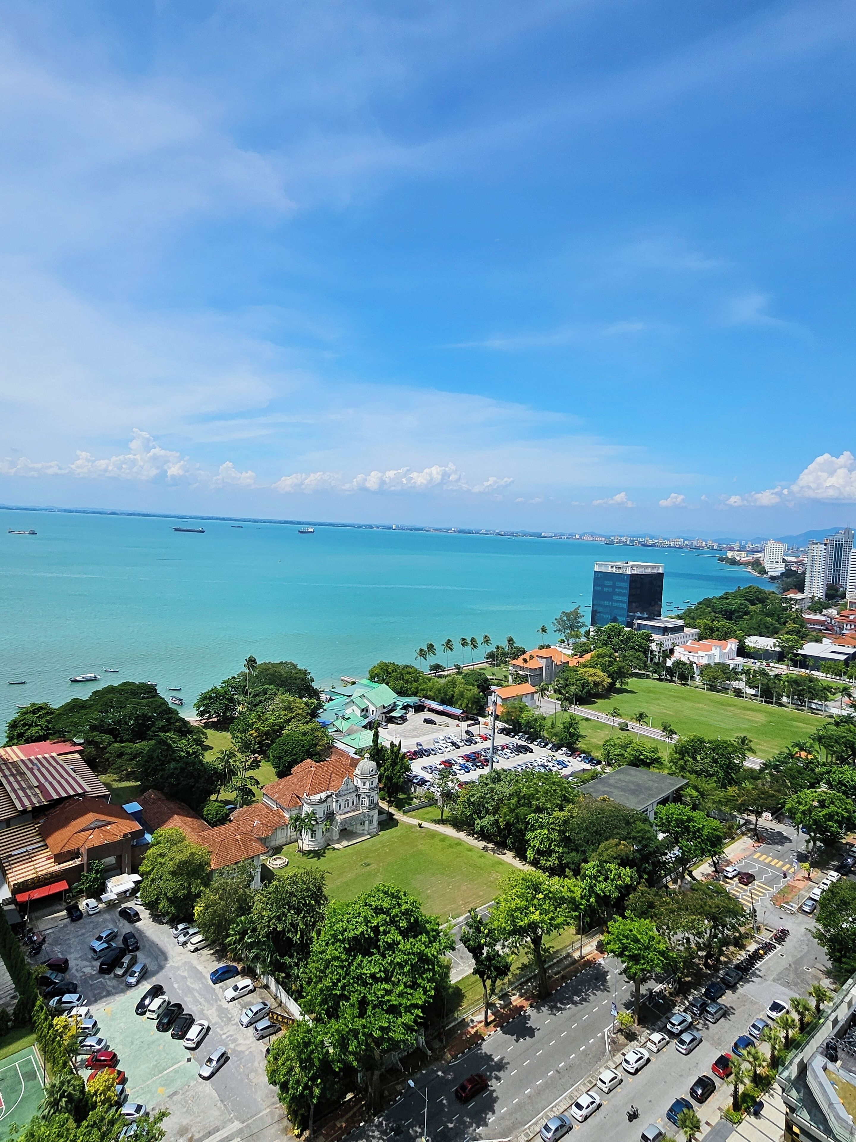 A coastal cityscape with a marina, a historic building, and modern high-rises.