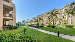 A hotel courtyard with a central pathway, palm trees, and a building with balconies.